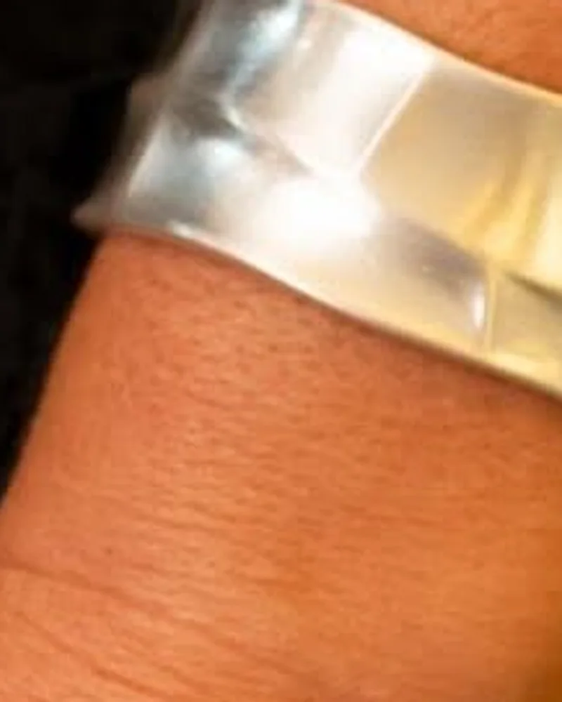 Bracelete prateado largo com superfície ondulada no braço