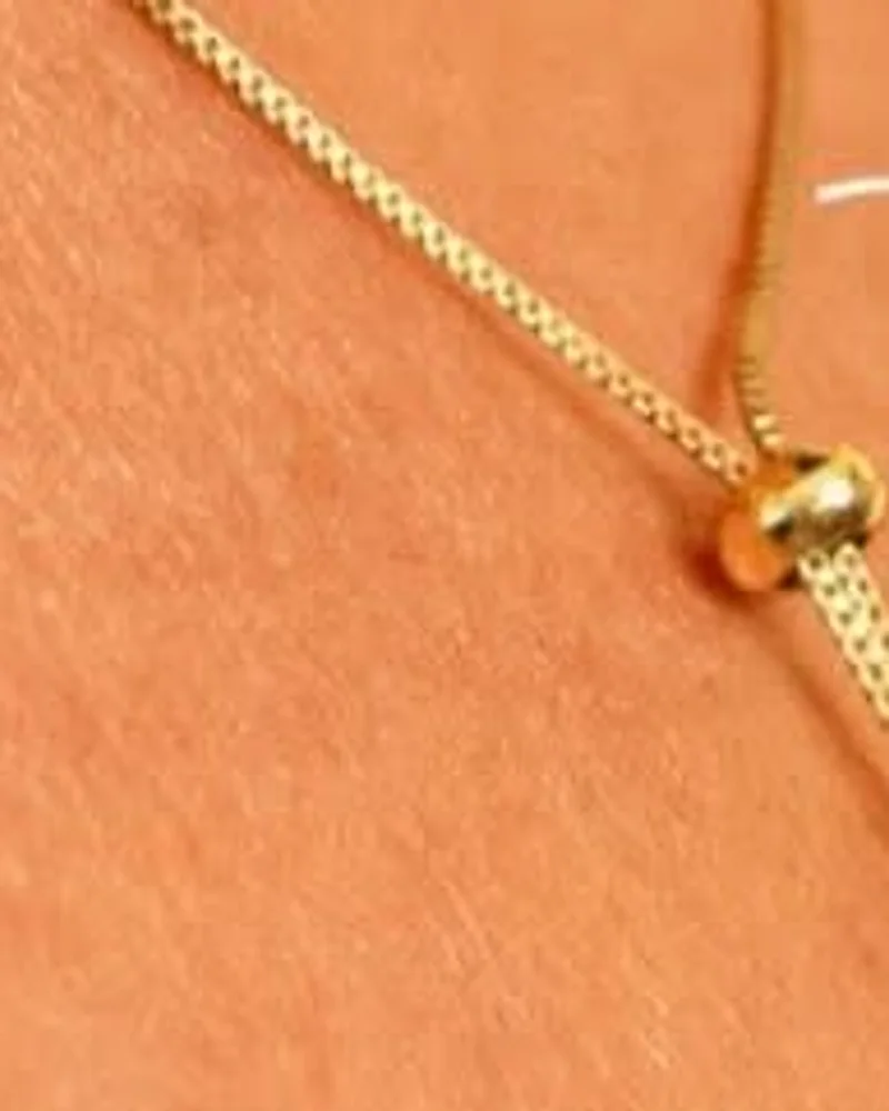 Colar dourado modelo gravatinha, com corrente que desliza e cai em V no colo