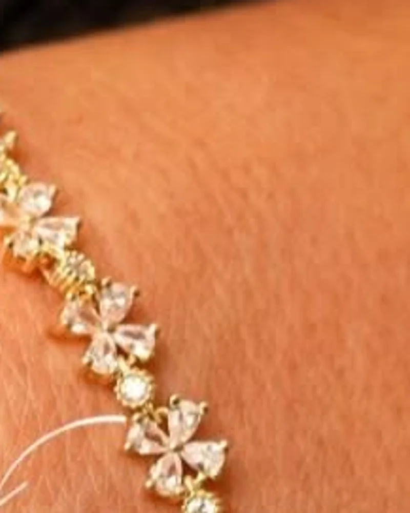 Pulseira riviera dourada com flores de zircônia lado a lado no pulso